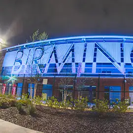 Birmingham stadium exterior lit with blue LED accent lighting at night