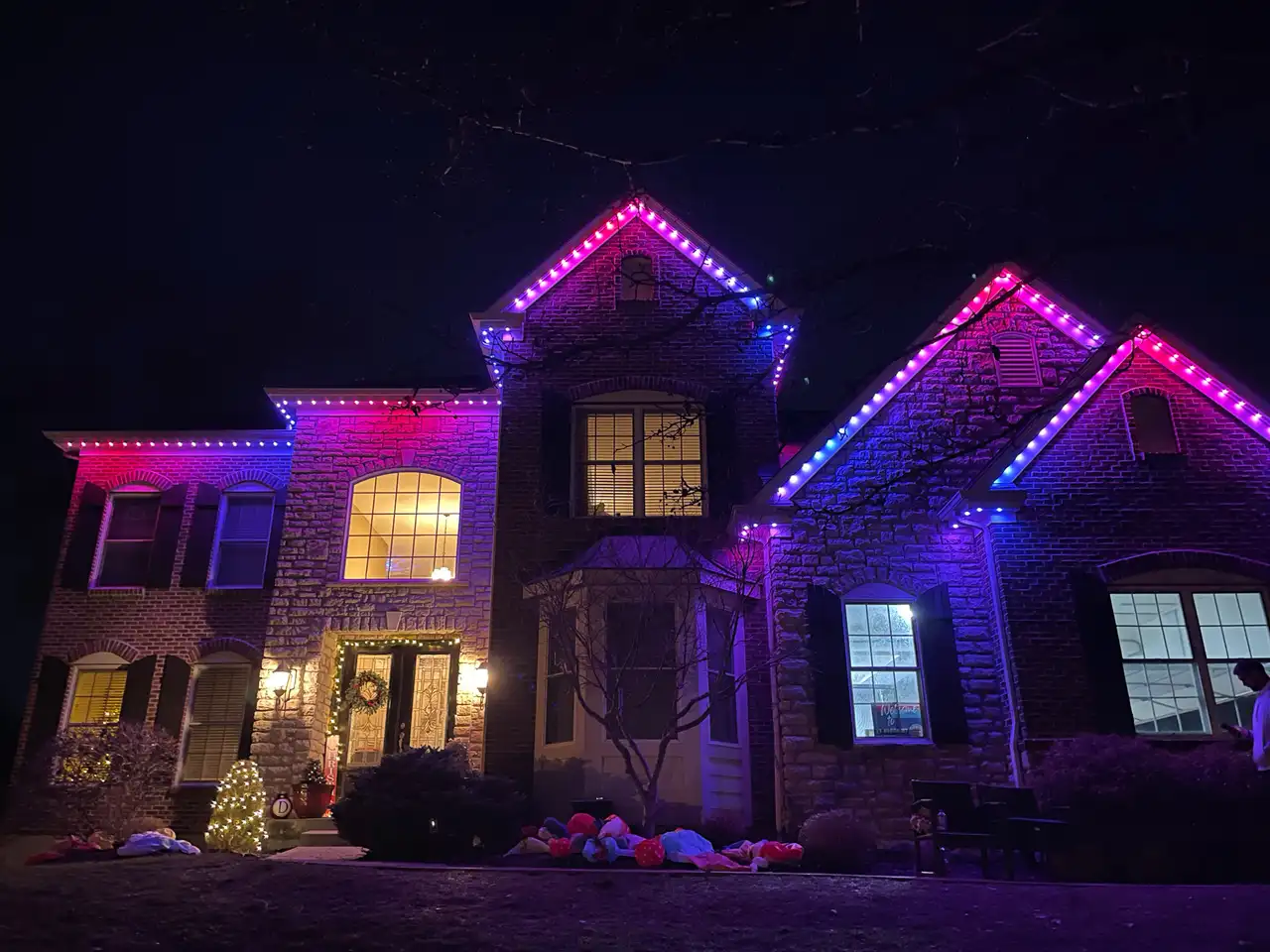 Brick and stone home in Madison, AL at night with pink, purple and blue permanent LED roofline lighting for Valentine's Day