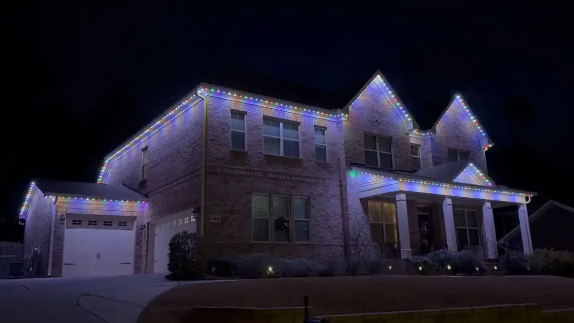 Two-story brick home in Owens Cross Roads, AL at night with multicolor permanent LED lighting along the rooflines