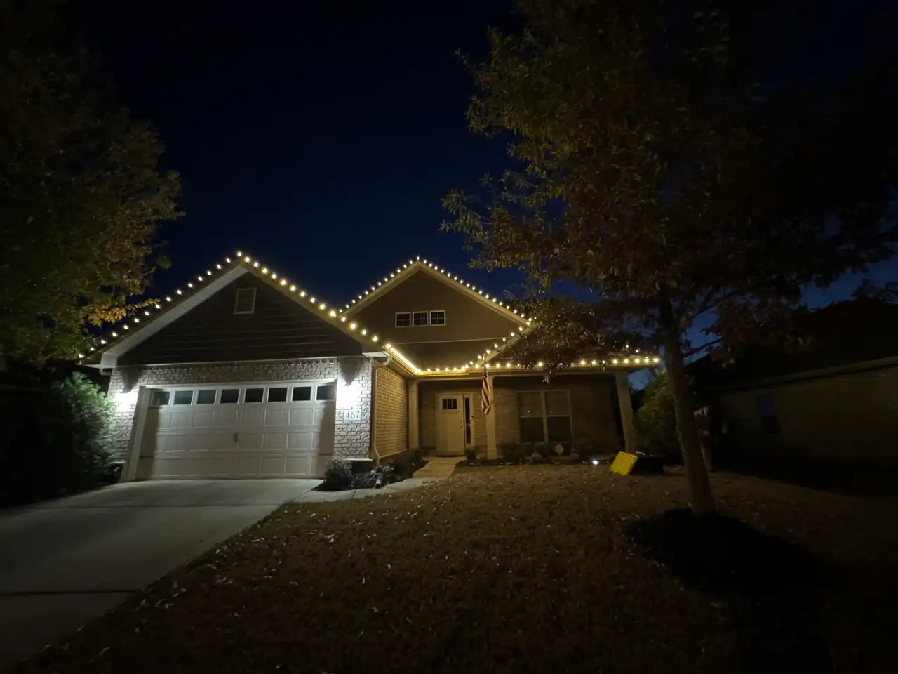 Home in the Huntsville area at night with warm white lights outlining the gables and roofline