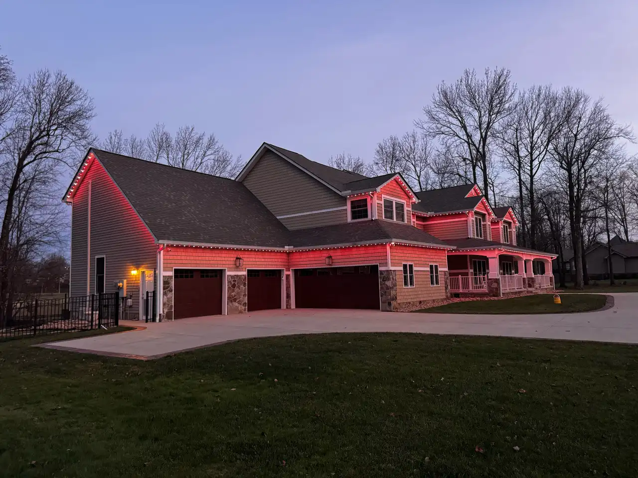 Home in the Chattanooga area at dusk with red permanent LED lighting along the rooflines above a three-car garage