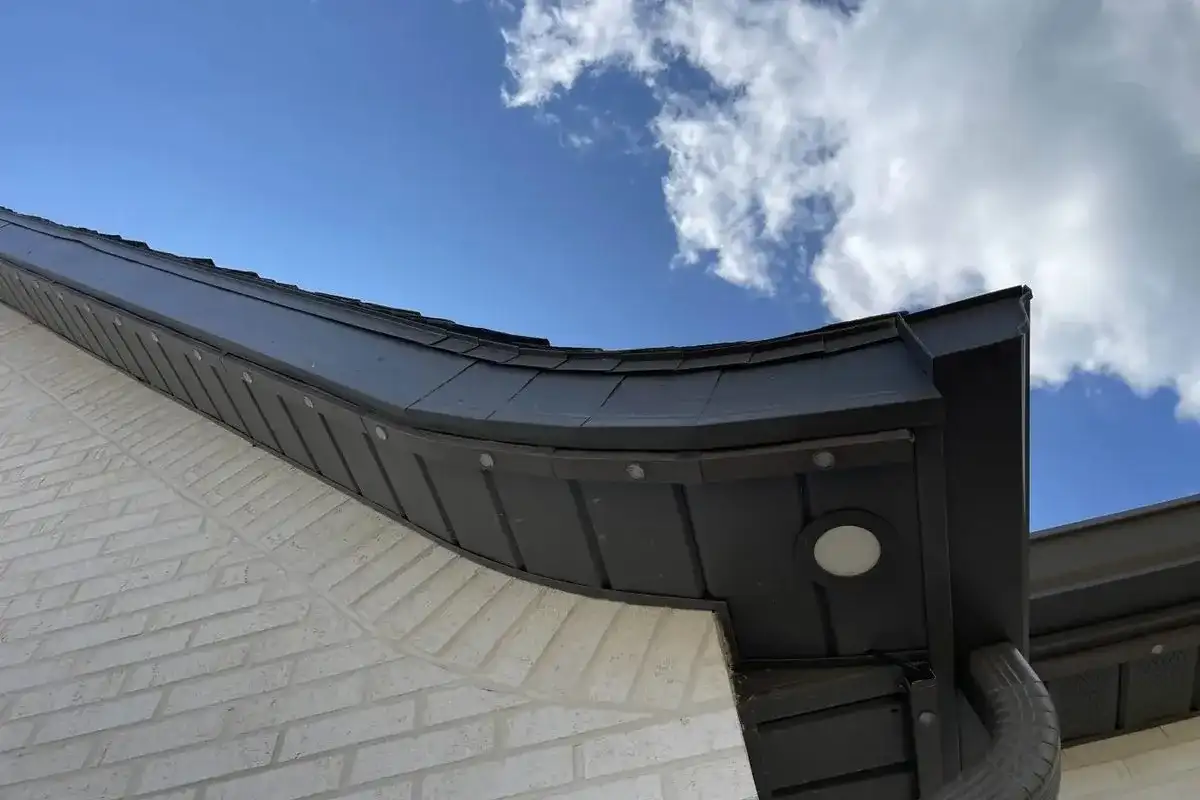 Daytime close-up of a permanent lighting track and fixture under the eave of a home
