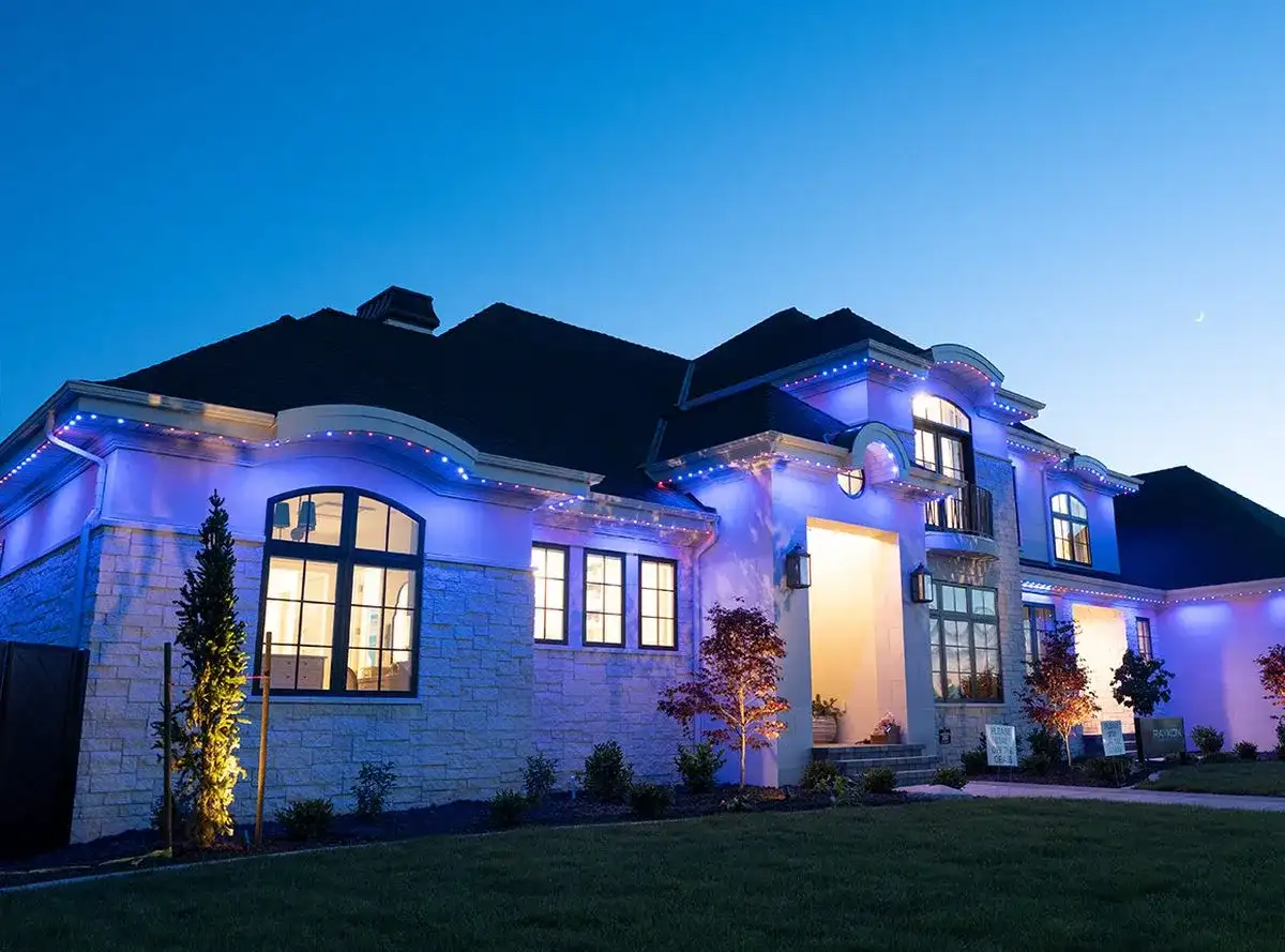 Large stone home at dusk with blue permanent lighting along every roofline